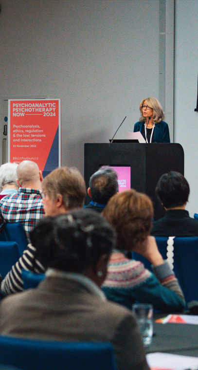 Woman presenting to audience at conference.