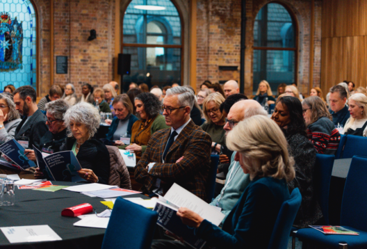 Conference audience consulting their paperwork in conference hall.