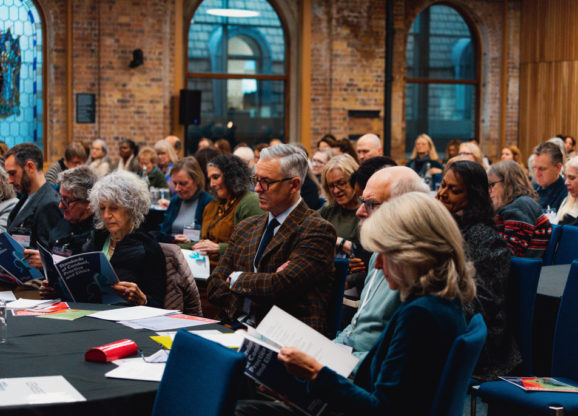 Conference audience consulting their paperwork in conference hall.